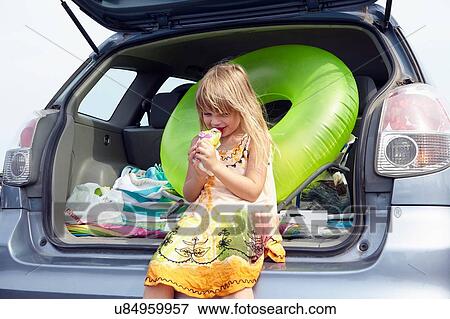 Stock Photo - Girl drinking at rear of car. Fotosearch