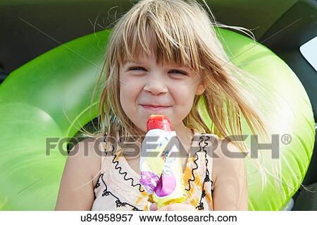 Stock Photo - Girl holding drink sitting at rear of car. Fotosearch