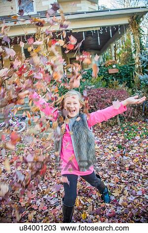 Stock Image - Girl playing with autumn leaves in garden. Fotosearch