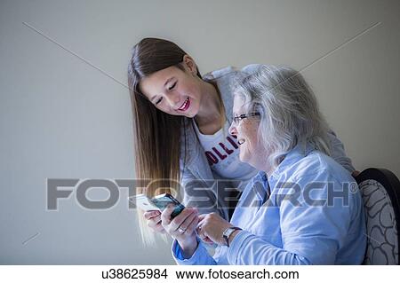 Picture - Girl showing grandmother smartphone. Fotosearch