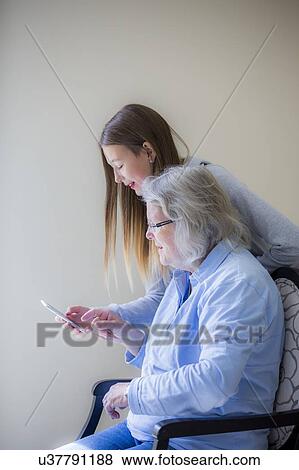 Girl showing grandmother smartphone View Large Photo Image Stock Photo - Girl showing grandmother smartphone. Fotosearch