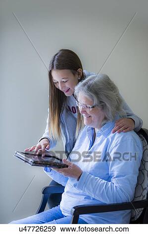 Girl showing grandmother tablet View Large Photo Image Stock Photo - Girl showing grandmother tablet. Fotosearch
