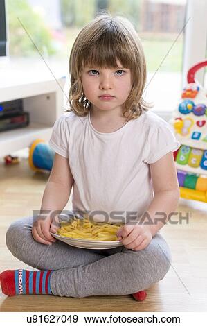 Stock Photo - Girl sitting on floor with french fries. Fotosearch