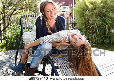 Girl sitting on mother's lap, leaning back View Large Photo Image Stock Image - Girl sitting on mother's lap, leaning back. Fotosearch