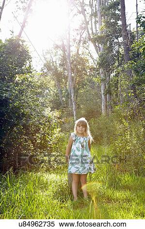 Stock Photography - Girl standing against tree in forest. Fotosearch