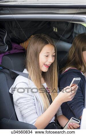 Girl using smartphone in car View Large Photo Image Picture - Girl using smartphone in car. Fotosearch