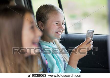 Stock Image - Girl using smartphone in car. Fotosearch