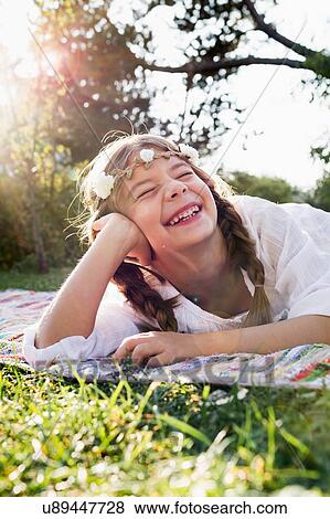 Stock Photo - Girl with flowers round head laughing with eyes closed. Fotosearch
