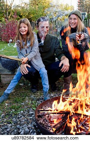 Girl with mother and father sitting in garden with fire pit View Large Photo Image Picture - Girl with mother and father sitting in garden with fire pit. Fotosearch