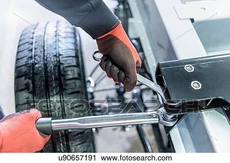 Stock Image - Gloved hands using spanner and ratchet on automotive production line. Fotosearch