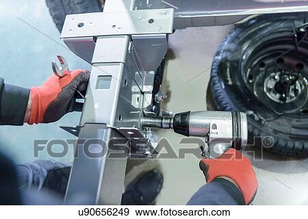 Stock Photo - Gloved hands using spanner and ratchet on automotive production line. Fotosearch