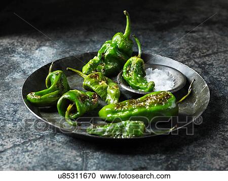 Stock Image - Green padron peppers in metal dish with bowl of sea salt. Fotosearch
