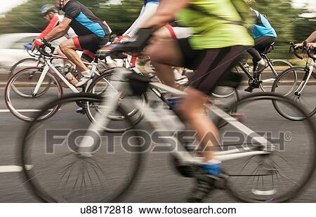 Group of racing cyclists speeding on urban road in racing cycle race View Large Photo Image Stock Photo - Group of racing cyclists speeding on urban road in racing cycle race. Fotosearch