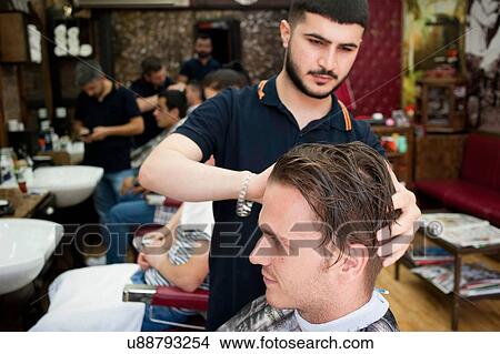 Hairdresser in barbershop cutting young mans hair View Large Photo Image Picture - Hairdresser in barbershop cutting young mans hair. Fotosearch