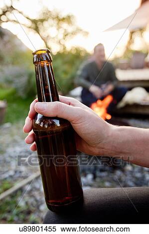 Stock Photography - Hand holding beer bottle, close up. Fotosearch