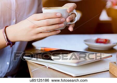 Hands of young woman holding coffee cup using digital tablet View Large Photo Image Stock Photograph - Hands of young woman holding coffee cup using digital tablet. Fotosearch