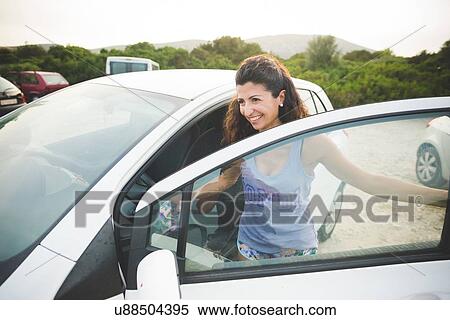 Stock Photography - Happy woman getting into car at the coast. Fotosearch