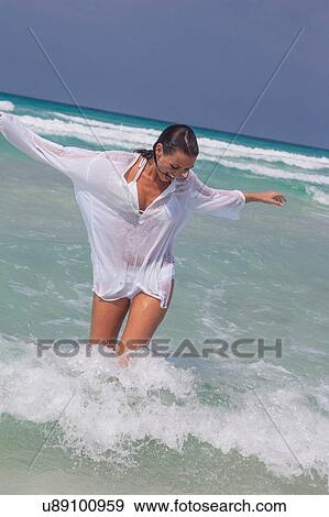 Stock Photo - Happy young woman running and splashing in sea, Majorca, Spain. Fotosearch