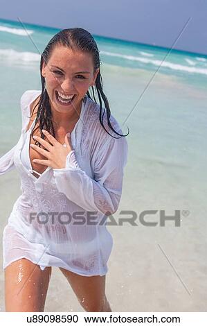 Stock Image - Happy young woman running out of sea with wet hair, Majorca, Spain. Fotosearch