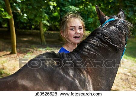 Stock Photo - Head and shoulders of girl with horse looking at camera smiling. Fotosearch