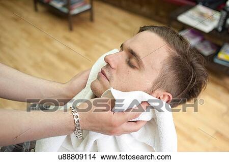 High angle side view of young man in barbershop, head back, eyes closed having face dried with towel View Large Photo Image Picture - High angle side view of young man in barbershop, head back, eyes closed having face dried with towel. Fotosearch