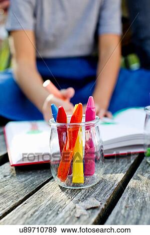 Stock Photo - Jar of crayons close up with girl in background. Fotosearch