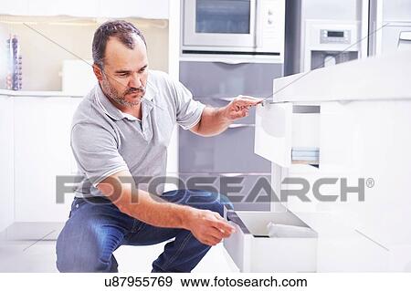 Stock Photo - Joiner installing drawers in kitchen. Fotosearch