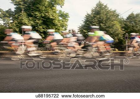 Stock Image - Large group of male cyclists speeding on urban road in racing cycle race. Fotosearch