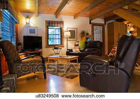 Stock Photo - Leather sofas and wooden coffee table in living room of Canadian cottage style log home. Fotosearch