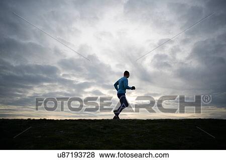 Low angle full length side view of runner against dramatic sky View Large Photo Image Stock Photo - Low angle full length side view of runner against dramatic sky. Fotosearch