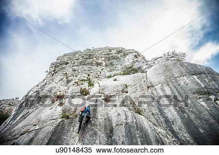 Low angle rear view of rock climber climbing up mountainside, Ogliastra, Sardinia, Italy View Large Photo Image Stock Photography - Low angle rear view of rock climber climbing up mountainside, Ogliastra, Sardinia, Italy. Fotosearch