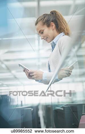 Low angle side view of young woman looking down using smartphone smiling View Large Photo Image Stock Image - Low angle side view of young woman looking down using smartphone smiling. Fotosearch
