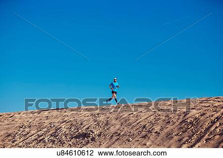 "Low angle view of blue sky and mid adult man running on sand dune, Dubai, United Arab Emirates" View Large Photo Image Stock Image - "Low angle view of blue sky and mid adult man running on sand dune, Dubai, United Arab Emirates". Fotosearch