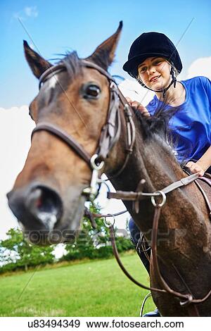 Low angle view of girl on horseback wearing riding hat smiling View Large Photo Image Stock Photo - Low angle view of girl on horseback wearing riding hat smiling. Fotosearch