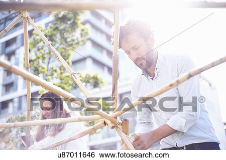 Low angle view of mature man in team building task building wooden structure smiling View Large Photo Image Stock Photograph - Low angle view of mature man in team building task building wooden structure smiling. Fotosearch