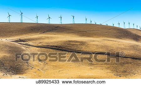 Stock Image - Low angle view of wind turbines on rolling landscape, California, USA. Fotosearch