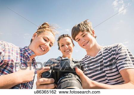 Low angle view of young man and female friends reviewing photographs on camera View Large Photo Image Stock Image - Low angle view of young man and female friends reviewing photographs on camera. Fotosearch