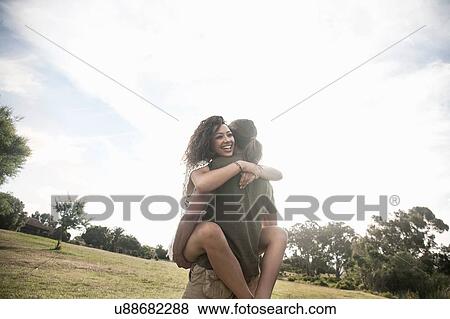 Low angle view of young man carrying smiling young woman View Large Photo Image Stock Photo - Low angle view of young man carrying smiling young woman. Fotosearch
