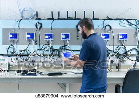 Picture - Male electrical engineer testing components in electronics factory. Fotosearch