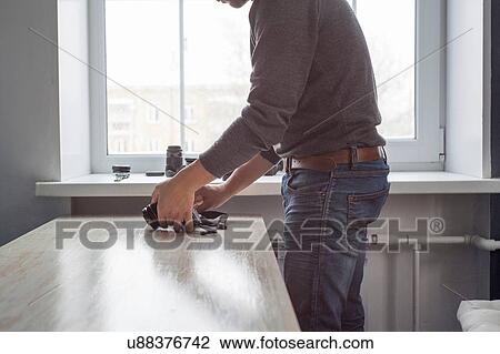 Stock Image - Male photographer checking camera on studio desk. Fotosearch