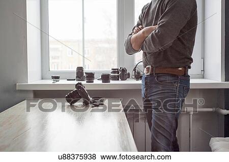 Stock Photo - Male photographer standing next to camera on studio desk. Fotosearch