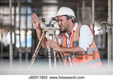 Male surveyor looking through theodolite on construction site View Large Photo Image Stock Image - Male surveyor looking through theodolite on construction site. Fotosearch
