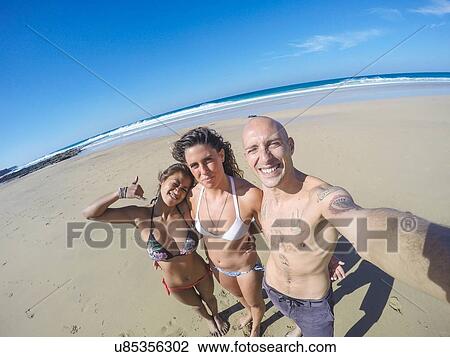 Man and two young women taking selfie on beach, El Cotillo, Fuerteventura, Spain View Large Photo Image Stock Image - Man and two young women taking selfie on beach, El Cotillo, Fuerteventura, Spain. Fotosearch
