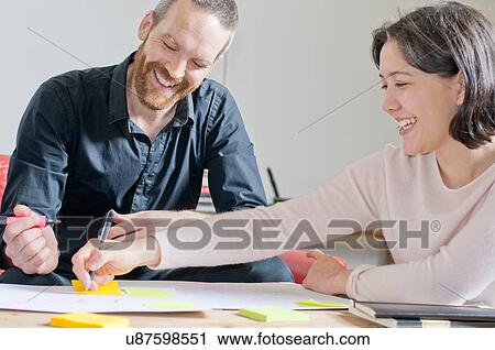 Stock Image - Man and woman laughing in meeting. Fotosearch