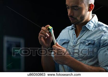 Stock Image - Man chalk rubbing pool cue. Fotosearch