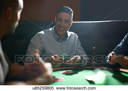 Stock Photography - Man dealing playing cards for game at pub card table. Fotosearch