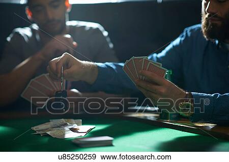 Stock Photo - Man gambling car key playing card game at pub card table. Fotosearch