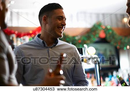 Stock Image - Man in public house looking away smiling. Fotosearch
