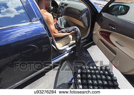 Picture - Man in wheelchair entering a car. Fotosearch
