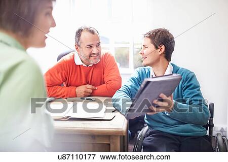 Man in wheelchair in office showing colleagues digital tablet, smiling View Large Photo Image Stock Photo - Man in wheelchair in office showing colleagues digital tablet, smiling. Fotosearch